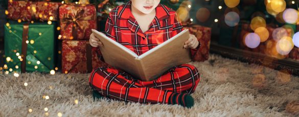 Child In Red Pajamas And Green Socks Reading Book On The Floor